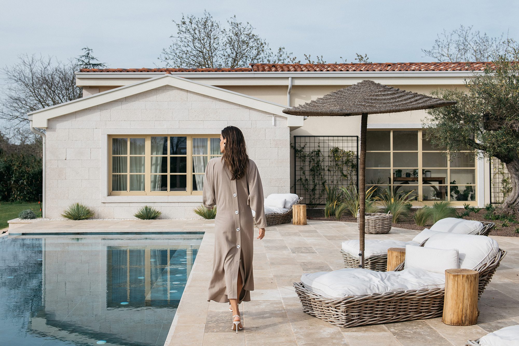 A guest walking the pool terrace toward the house at LaMaison