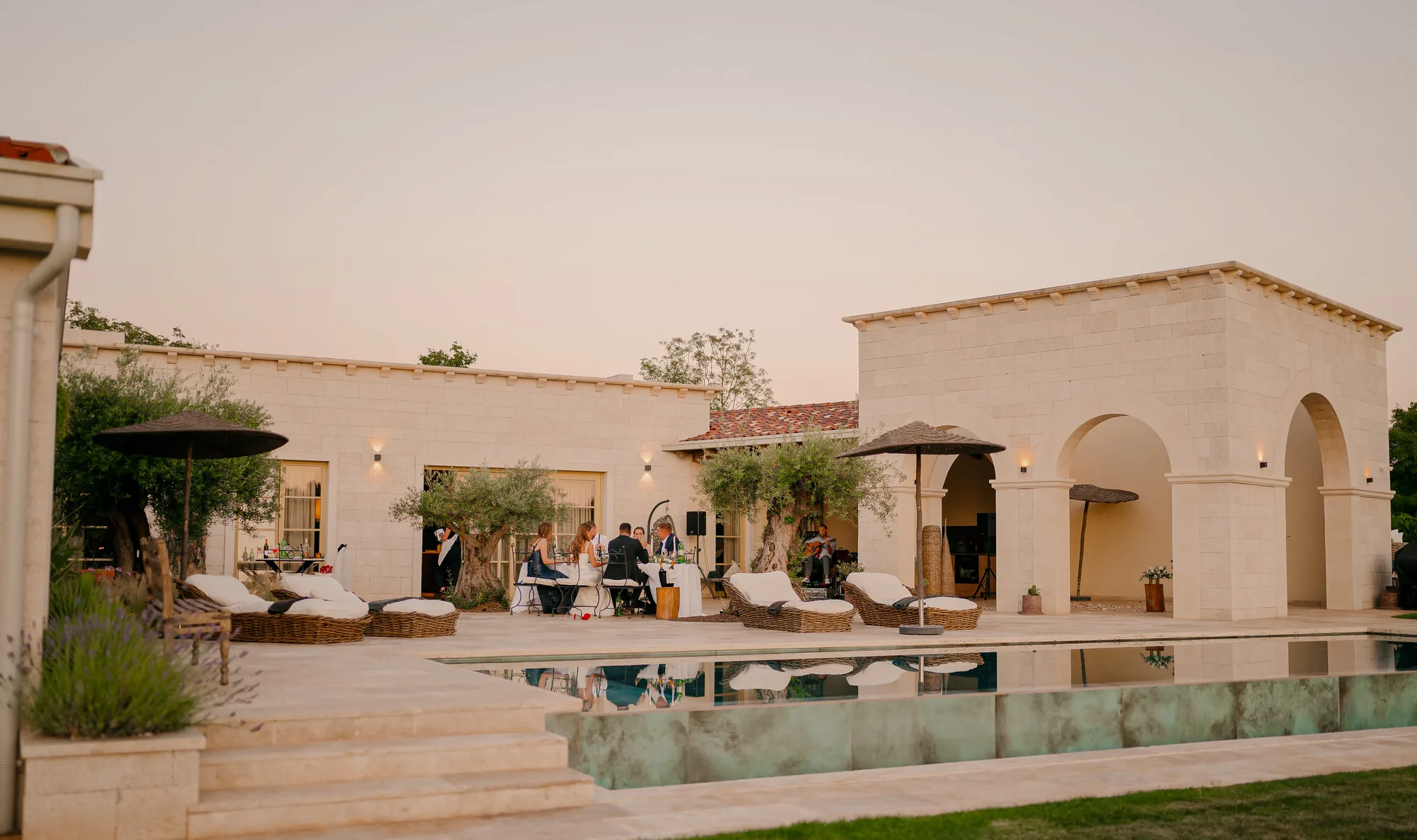 Guests dining by the pool at dusk at LaMaison, a guitarist playing beneath the arches, inland Istria