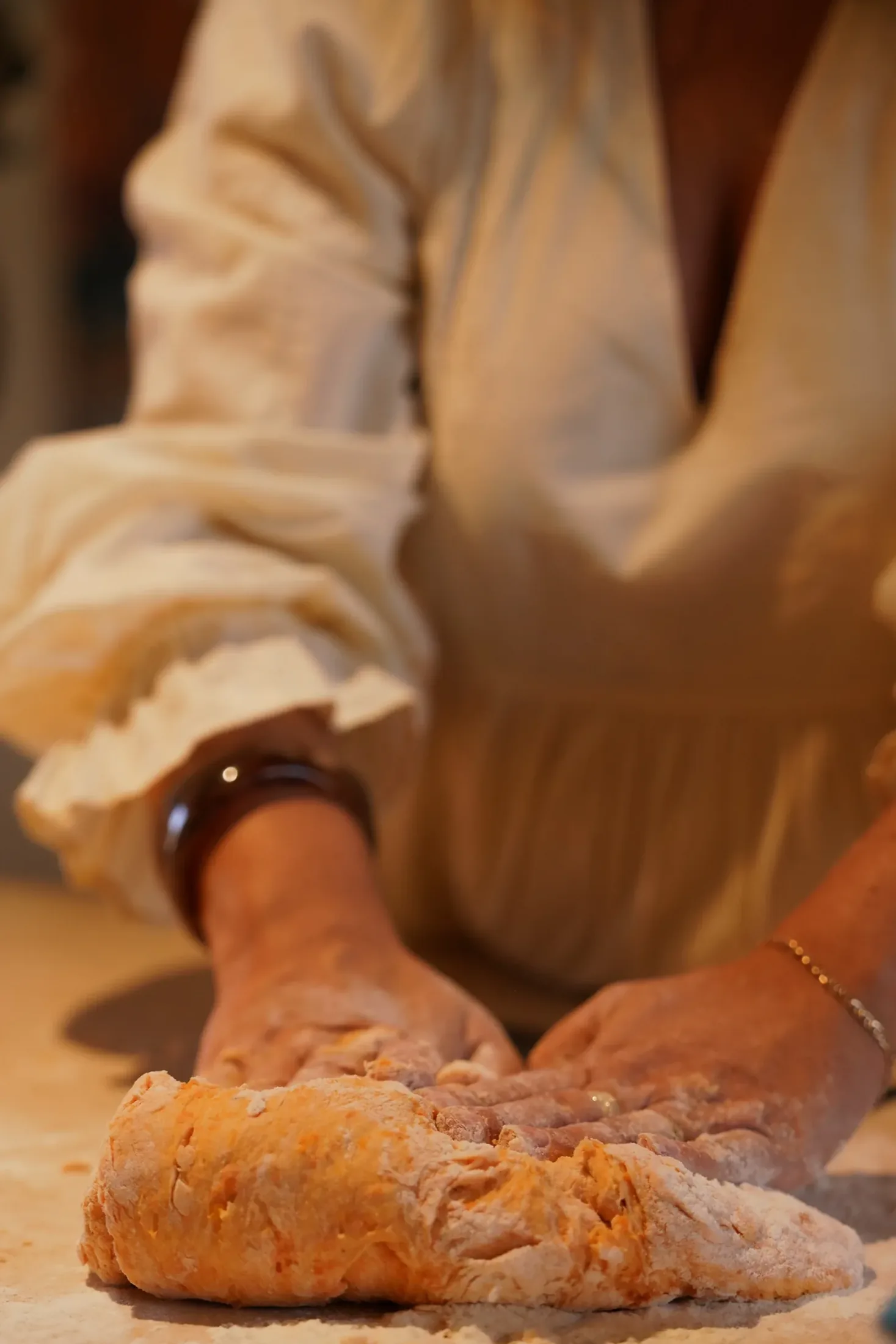 Hands kneading pumpkin gnocchi dough on a floured table