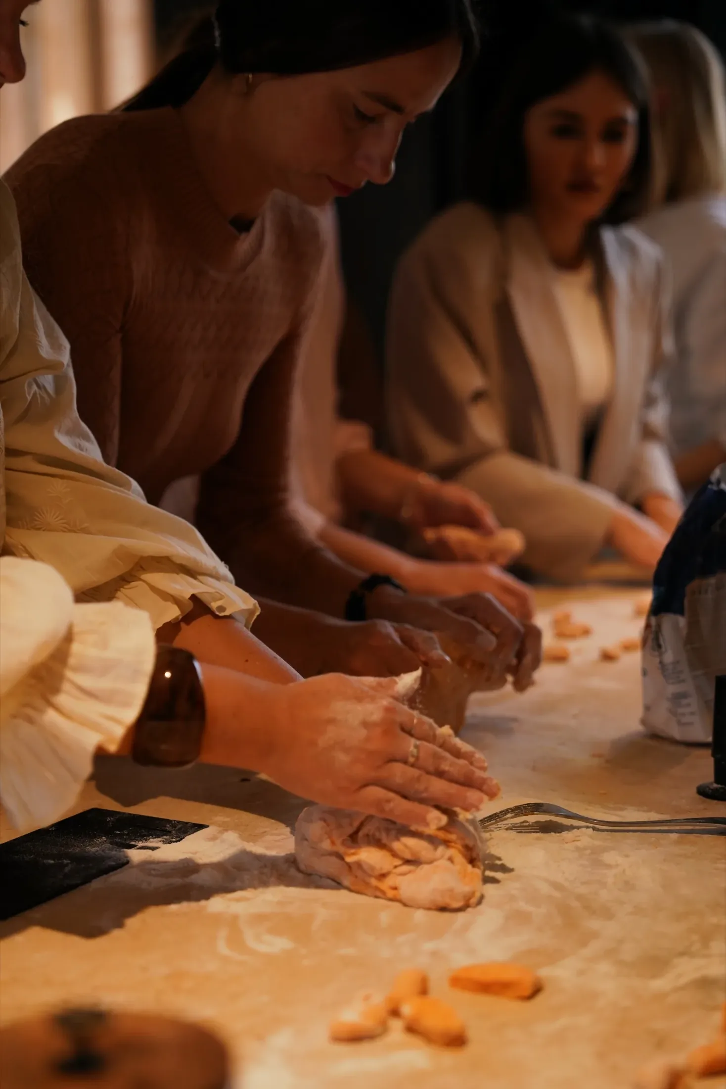 Guests shaping gnocchi together at the long floured table
