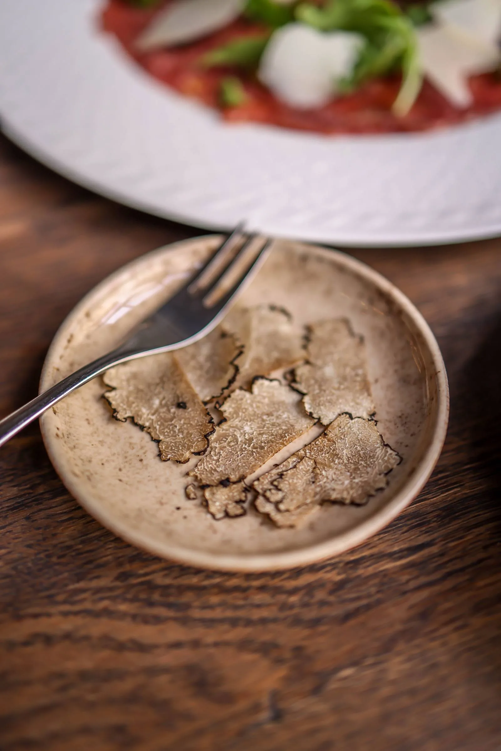 White truffle shaved over carpaccio at the table at LaMaison
