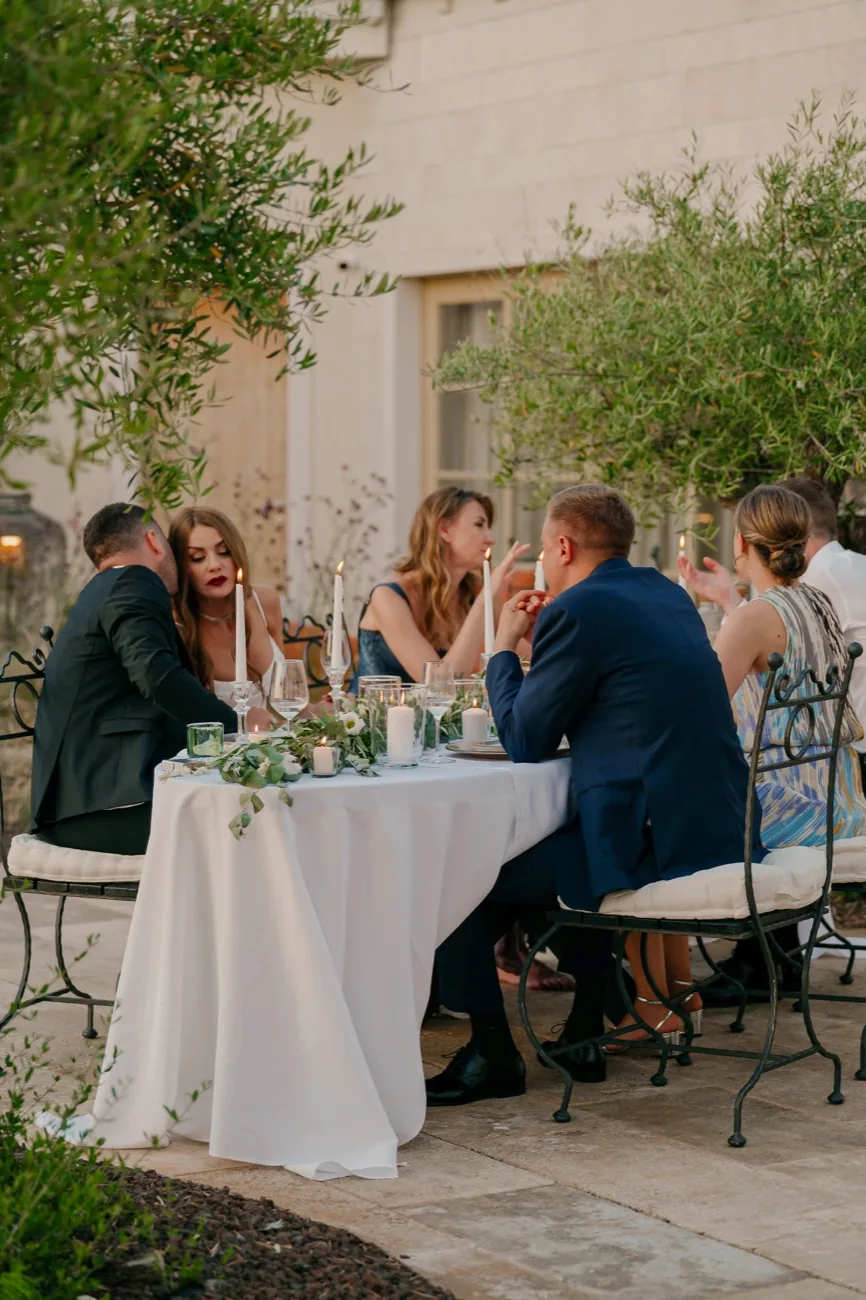 Guests seated at a candlelit dinner in the garden at LaMaison as the evening light fades